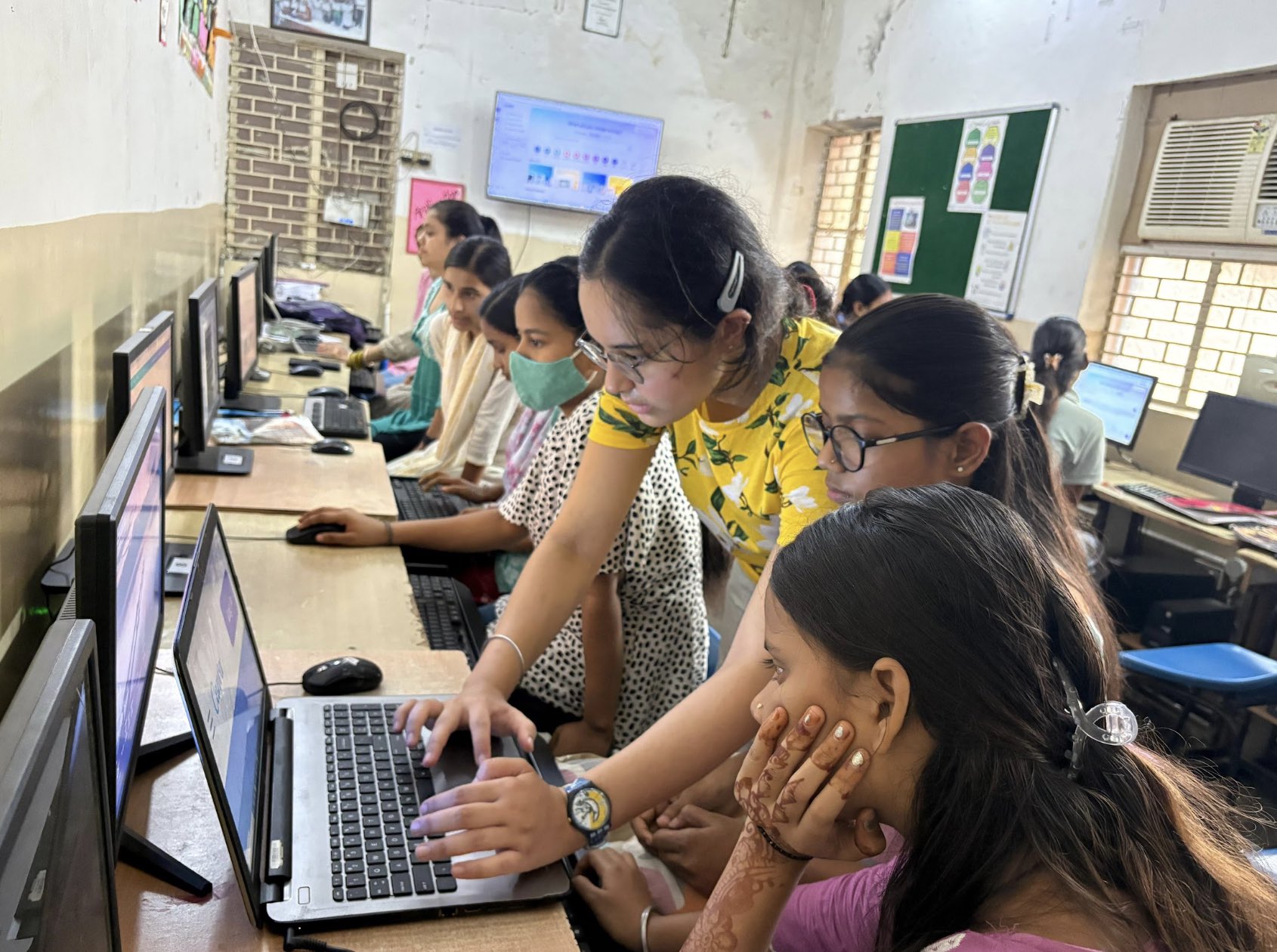 Mehak leaning over a laptop to guide a participant in a computer lab